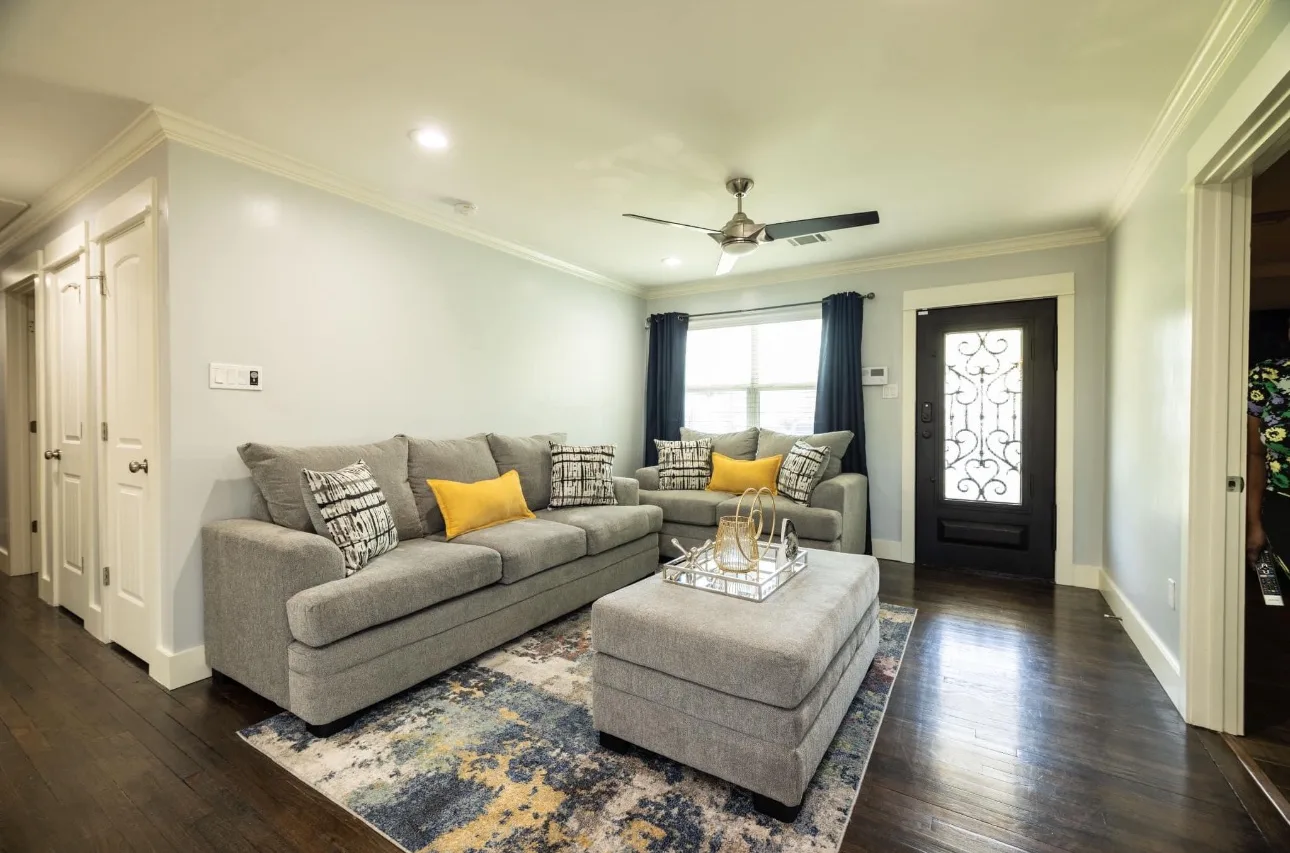 Bright living room with sofas, ottoman and hardwood floors cleaned by Pristine Cleaning