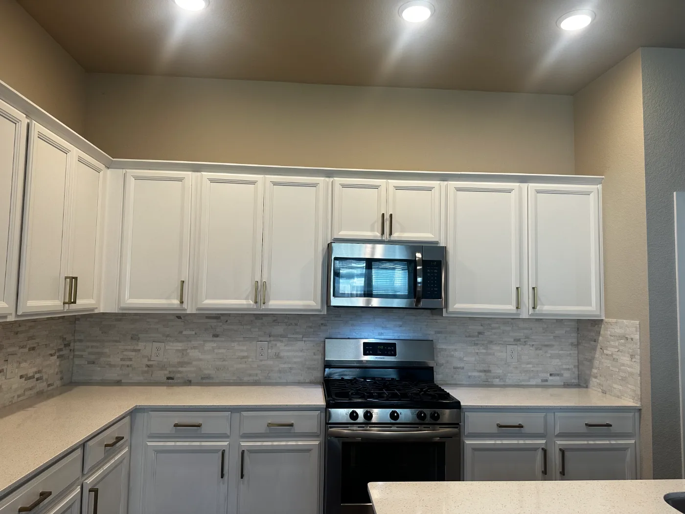 White kitchen cabinets, backsplash, range and counters cleaned and polished